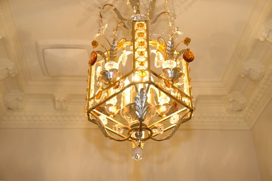 Gilt and crystal lantern hanging in a plastered entry hall