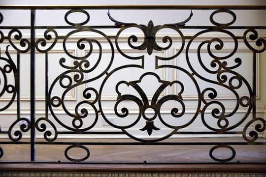 Scrolled wrought iron balcony railing on an interior landing